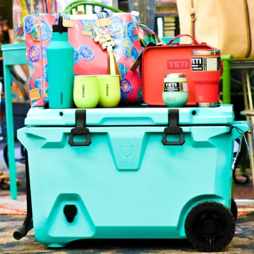 Neon blue cooler with bottles and bags sitting on top of it