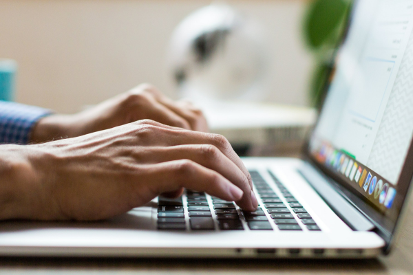 Individual typing on a laptop